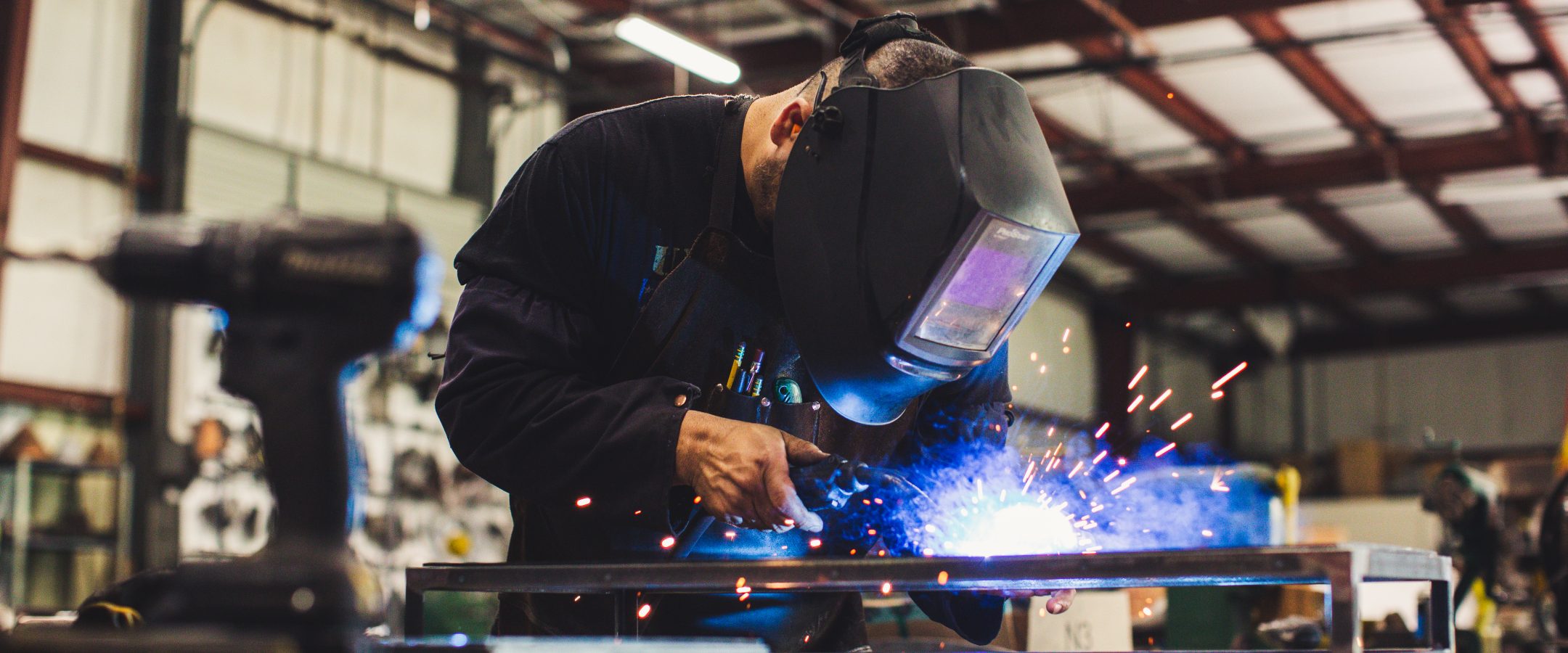 A welder wearing protective gear  is torching metal.