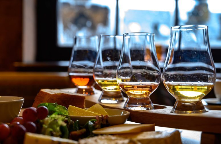 asting of original scottish cheese and whisky, plate with scottish cheeses and variety of Scotch in glasses in pub