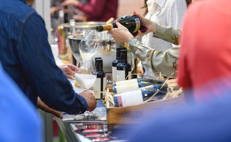 Midsection of hostess serving wine at wine fair event