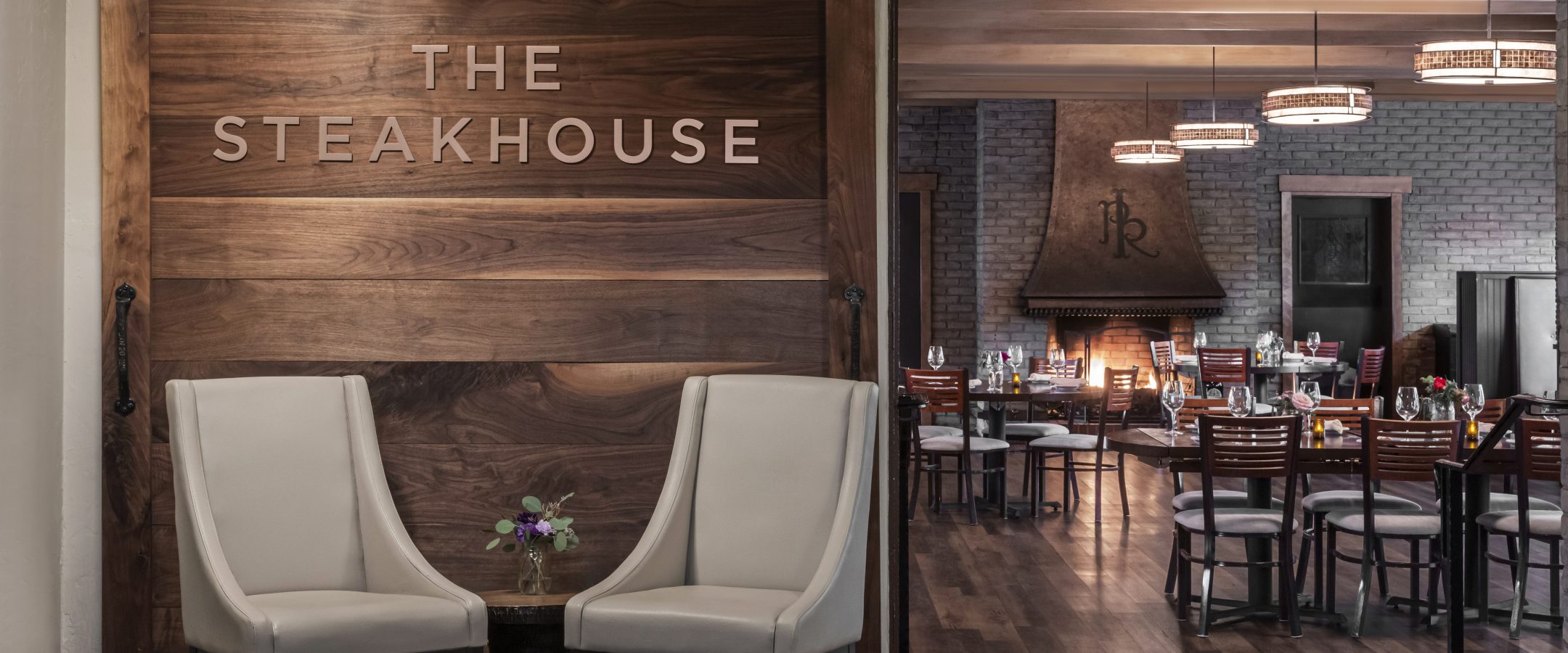 Two chairs at the entrance of a restaurant. The sign on the wall reads steakhouse