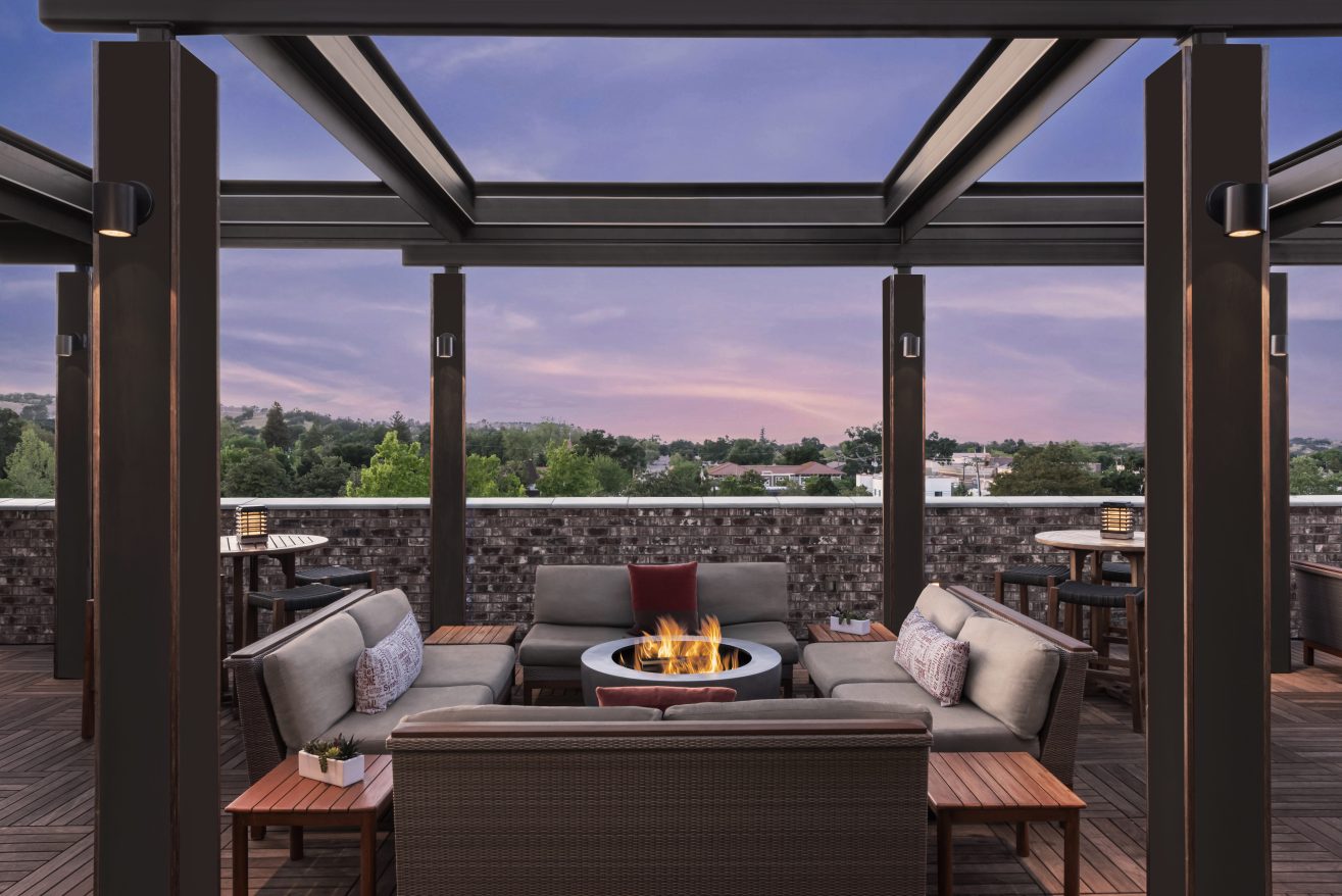 Rooftop deck at sunset. Two chairs are positioned by a firepit and the sky is purple.