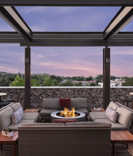 Rooftop deck at sunset. Two chairs are positioned by a firepit and the sky is purple.