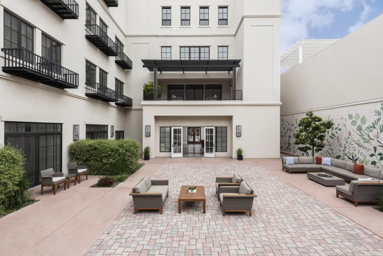 A modern outdoor courtyard with brick flooring, featuring seating arranged around a central table.