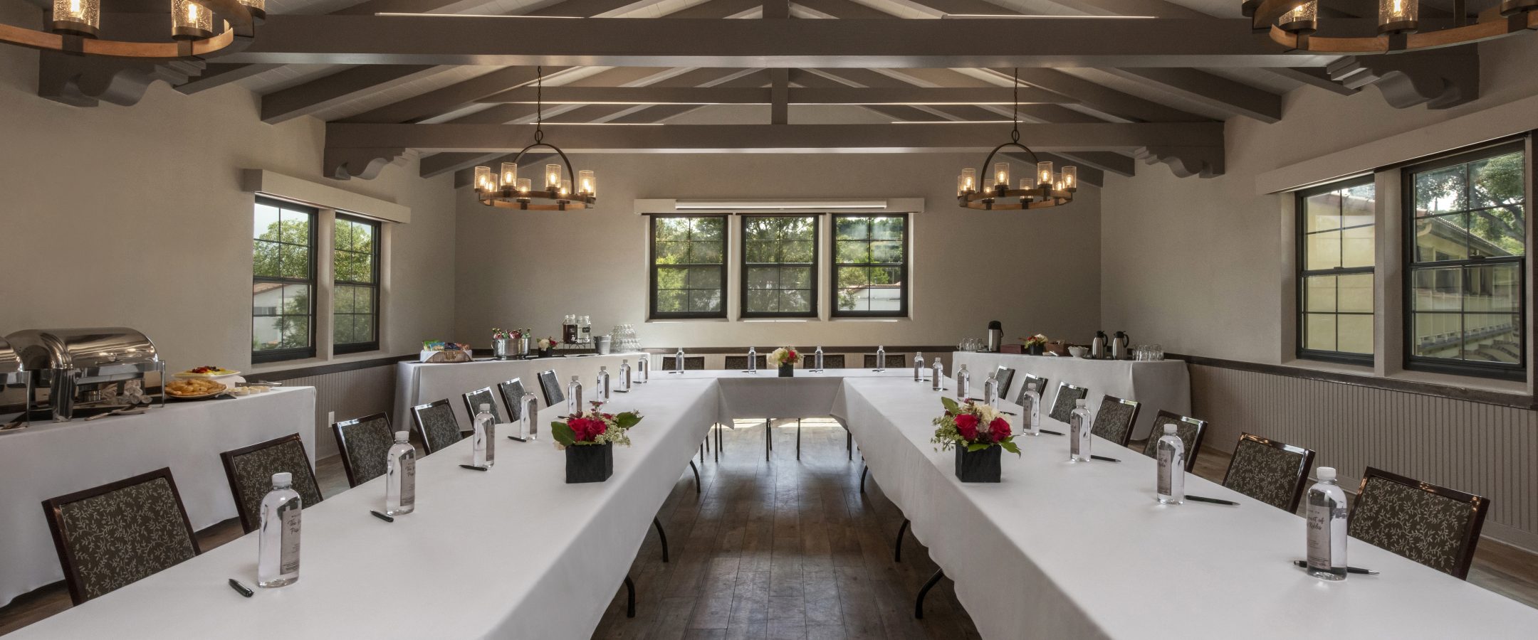 A meeting room featuring a U-shaped table draped in a white tablecloth, with bottles of water placed in front of each seat.