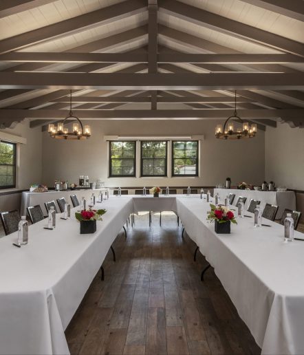 A meeting room featuring a U-shaped table draped in a white tablecloth, with bottles of water placed in front of each seat.