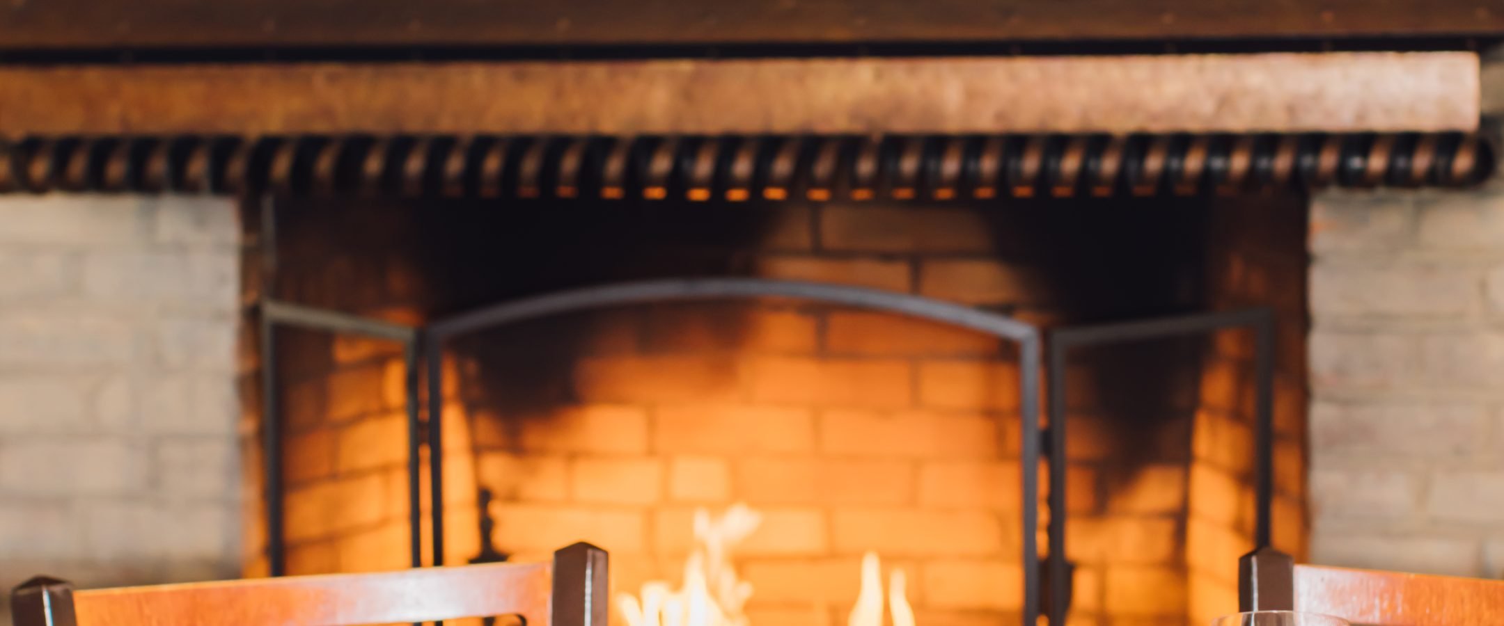 Close up of dinner plates on a table with a roaring fire behind.