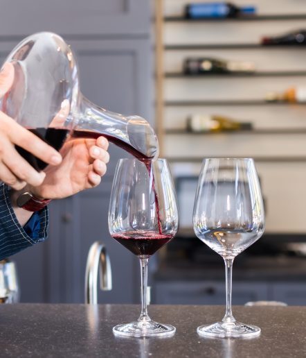 Closeup of a person pouring wine from a decanter into wine glasses