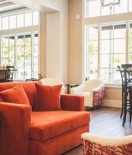 A red sofa in a lounge with large windows behind it.