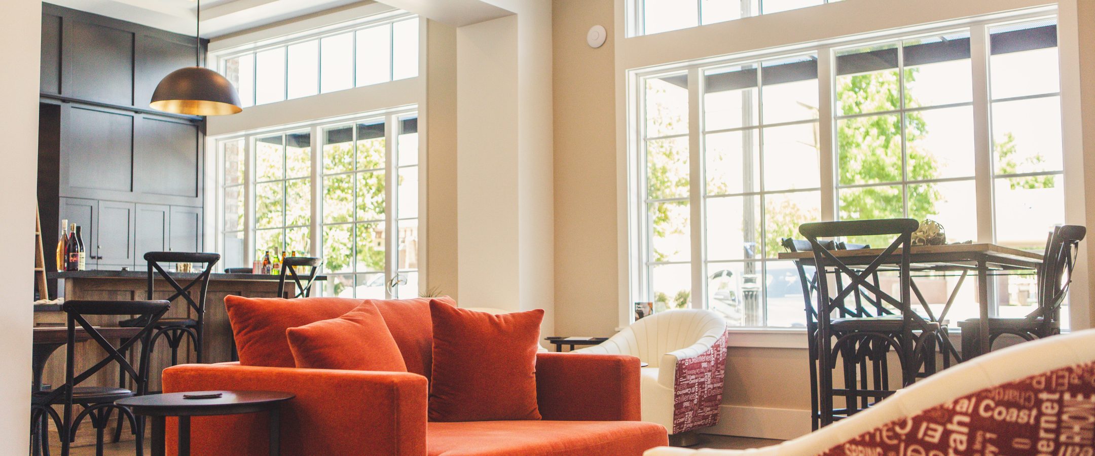 A red sofa in a light filled room with tall windows