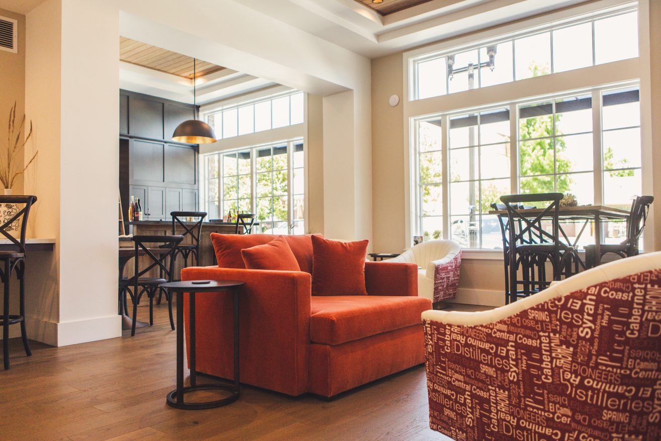 A lounge with a red sofa in a room with tall windows.