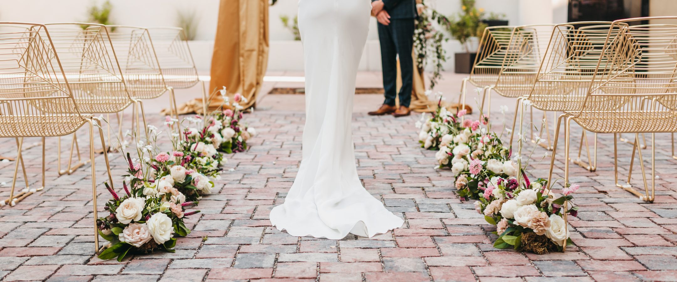 A bride walking toward the groom down the aisle lined with flowers