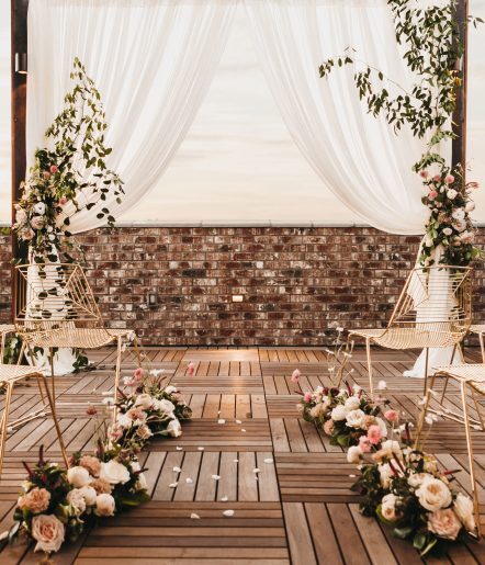 A rooftop alter adorned with floral arrangements and white sheets.