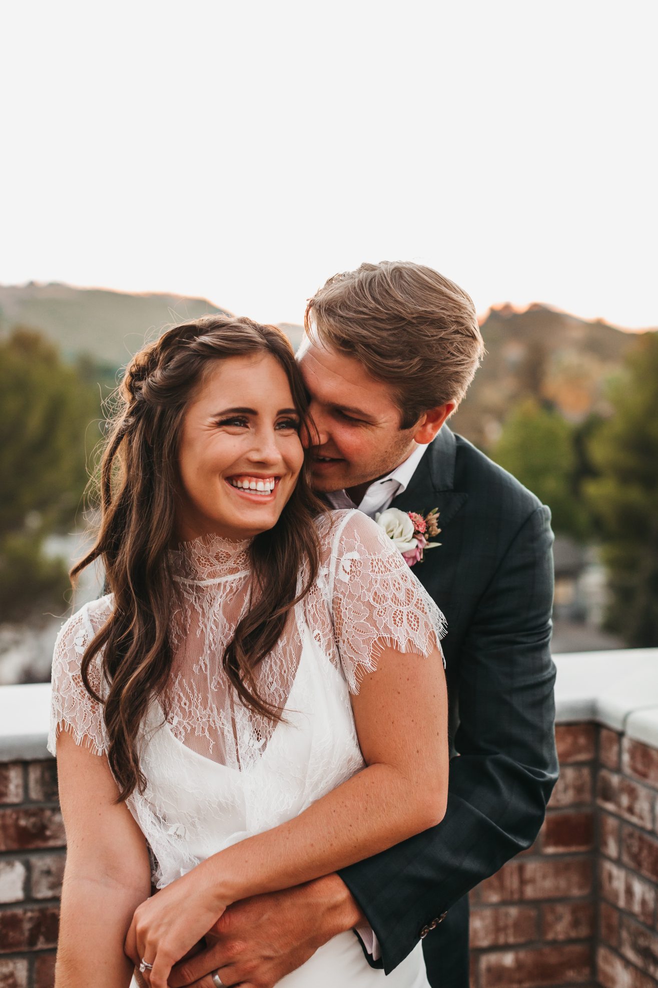 A happy bride and groom embracing each other on an outdoor rooftop.