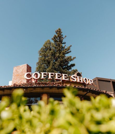 The entrance to a restaurant with a Coffee Shop sign in big letter above the door.