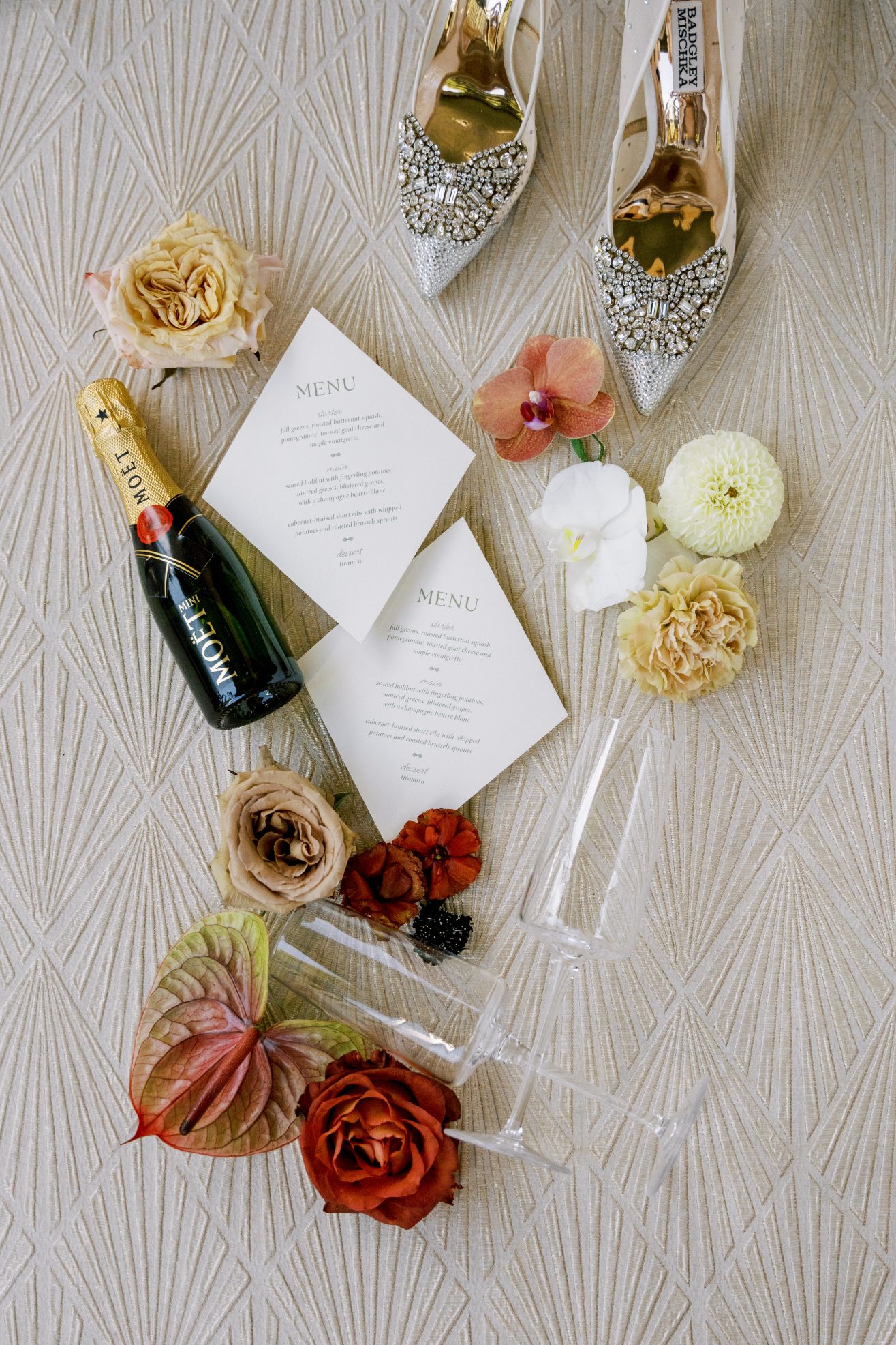 Weddings invitations, mini Moet Chandon bottle, champagne glasses, and sparkly shoes.